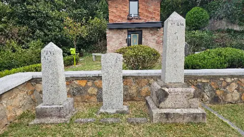 A cemetery with three gravestones and a brick wall