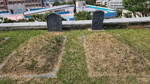 A cemetery with two headstones and a grassy area