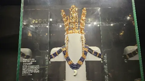 A gold crown is on display in a glass case