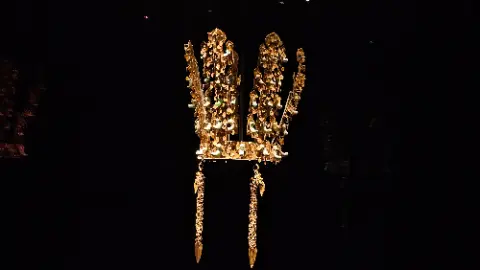 A golden crown with a chain hanging from it