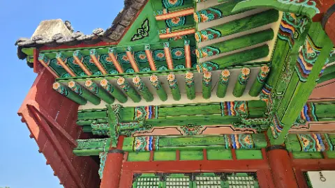 A green and red building with a wooden roof