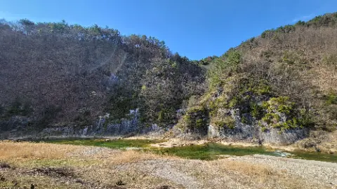 A green river flows through a valley with a mountain
