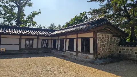 A house with a shingled roof and a stone wall