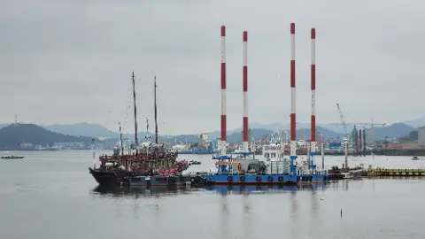 A large boat is docked in a harbor with other