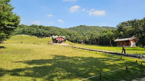 A large grassy field with a small building in the
