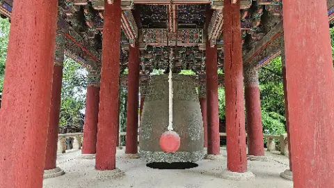 A large red and gold bell hangs from a red