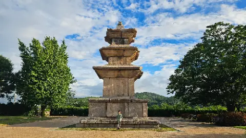 A man stands in front of a large stone monument