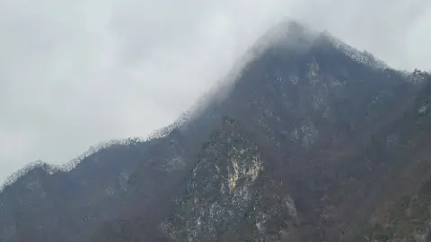 A mountain with a cloudy sky above it