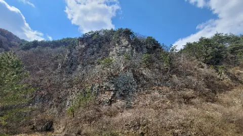 A mountain with a rocky cliff and a blue sky