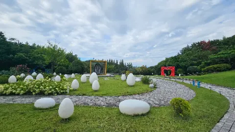 A park with a pathway and white rocks and eggs