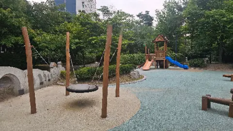 A playground with a swing, slide, and a small house