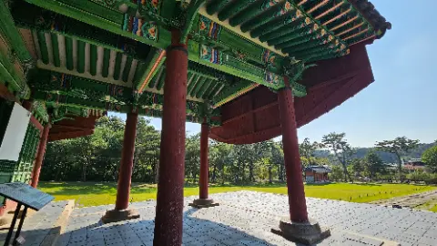 A red and green roofed building with a stone pillar