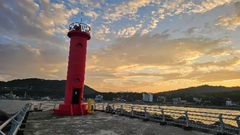 A red lighthouse with a yellow door and a white