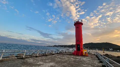 A red lighthouse with a yellow top is on a