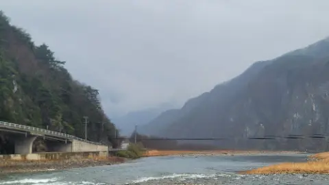 A river with a bridge and a mountain in the