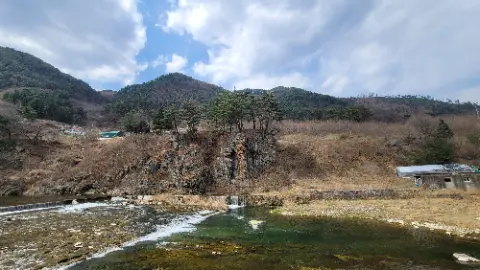A river with a waterfall and a mountain in the