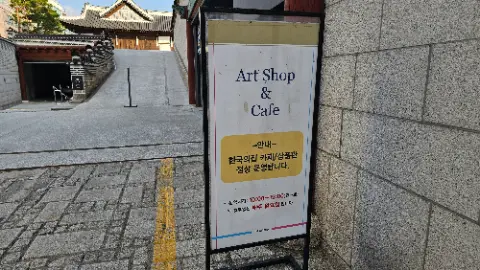 A sign for an art shop and cafe is posted