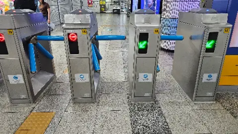 A silver subway turnstile with a green light on the