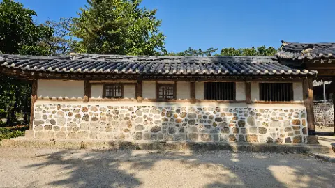 A small building with a stone wall and a wooden