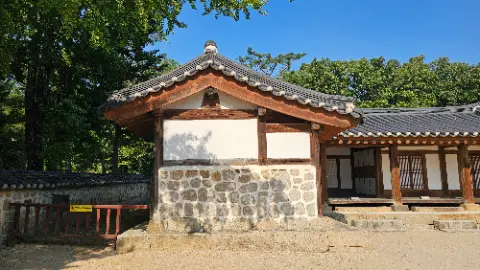 A small building with a tile roof and a stone