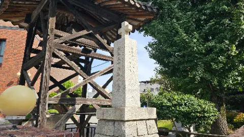 A stone monument with a cross on top is located