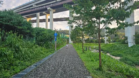 A woman walking on a path under a bridge