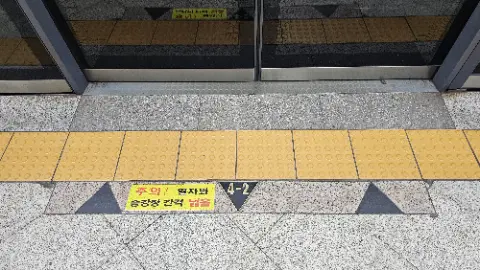 A yellow and black sign with a triangle on it