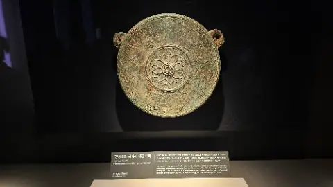 An ancient bronze bowl with a flower design on it
