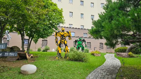 Two robot statues are standing in a grassy area